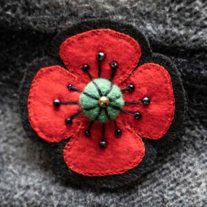 Four red petal flower with black border and green felt centre. Bead stamen.